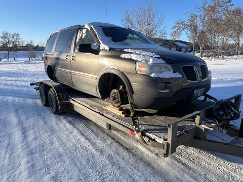 Snow-Covered Van on Trailer for Scrap Metal Pickup