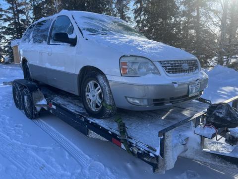 Snow-Covered Van on Trailer for Scrap Metal Pickup in Saskatchewan