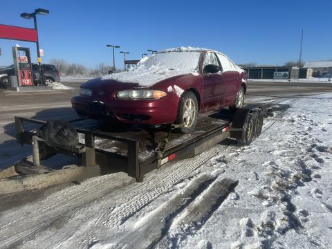 Snow-Covered Car on Trailer for Scrap Metal Pickup