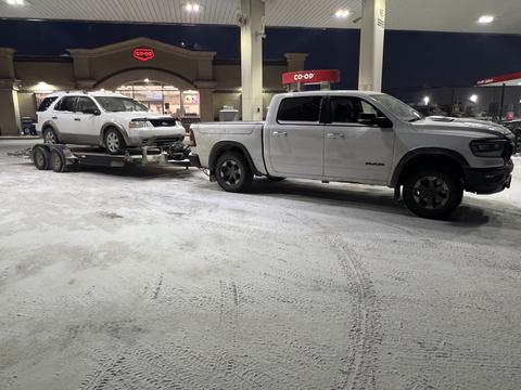 Pickup Truck Towing Scrap Vehicle at Gas Station